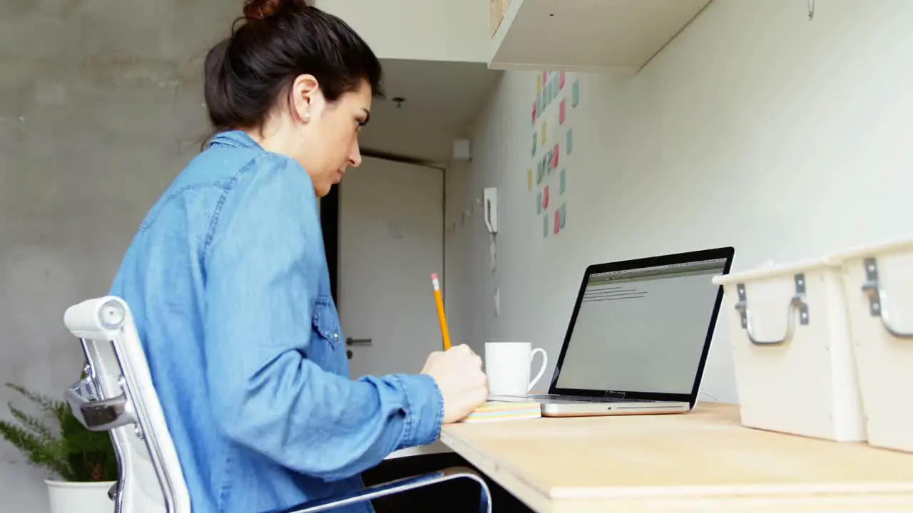 Female executive writing on sticky notes at desk