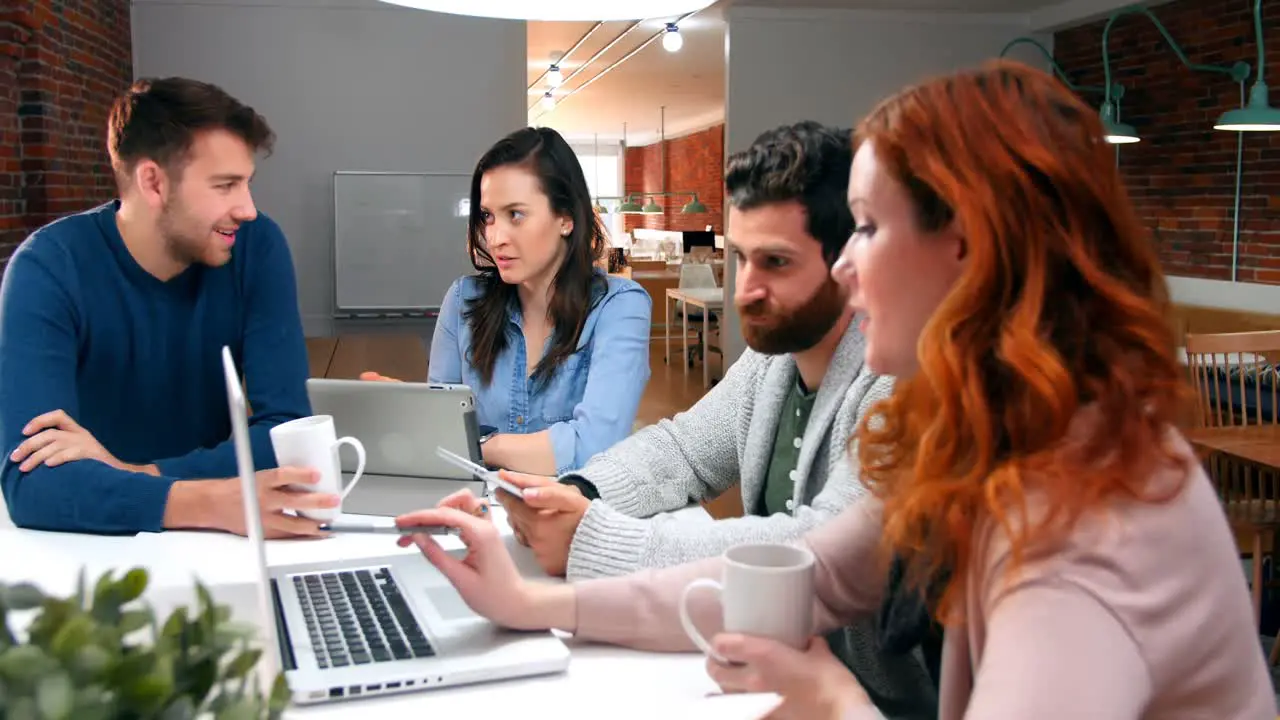 Business executives discussing over digital tablet and laptop