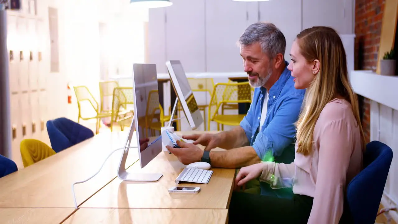 Business executives using digital tablet while disusing over computer