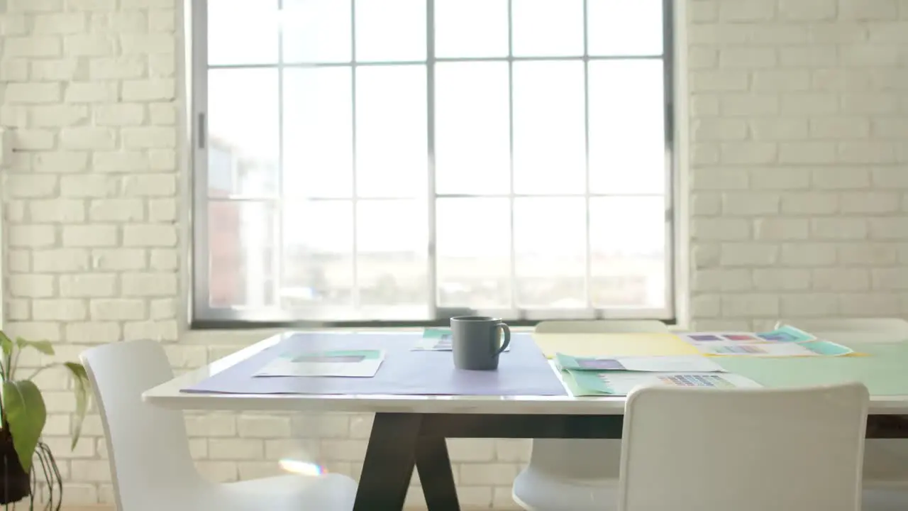 Empty white creative office with documents and cup of coffee on table in slow motion