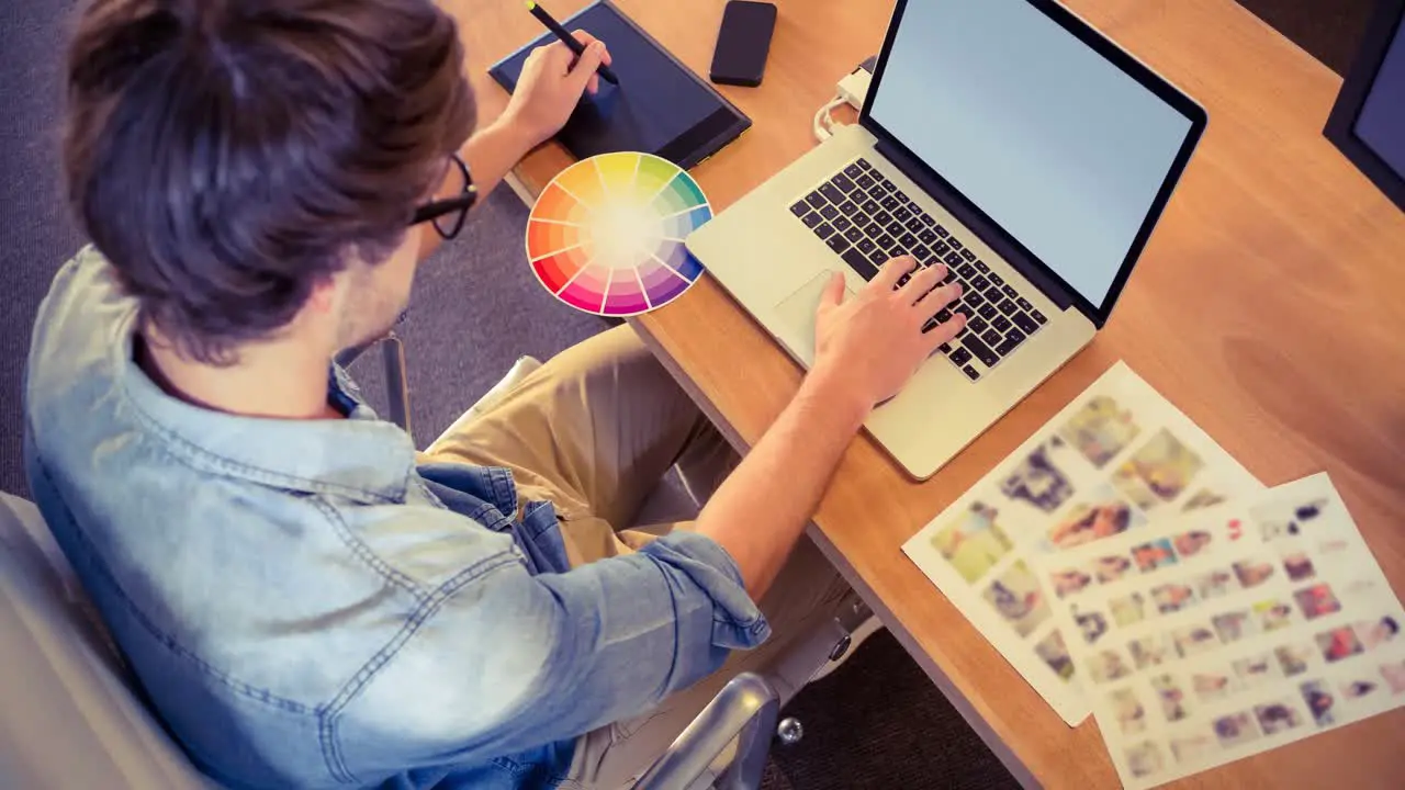 Video of creative man using graphic digital tablet and laptop in modern office