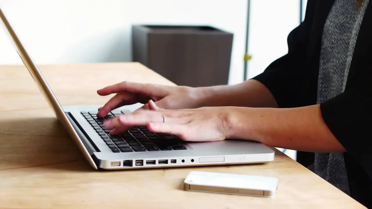 Mid section of female executive sitting at desk and using laptop