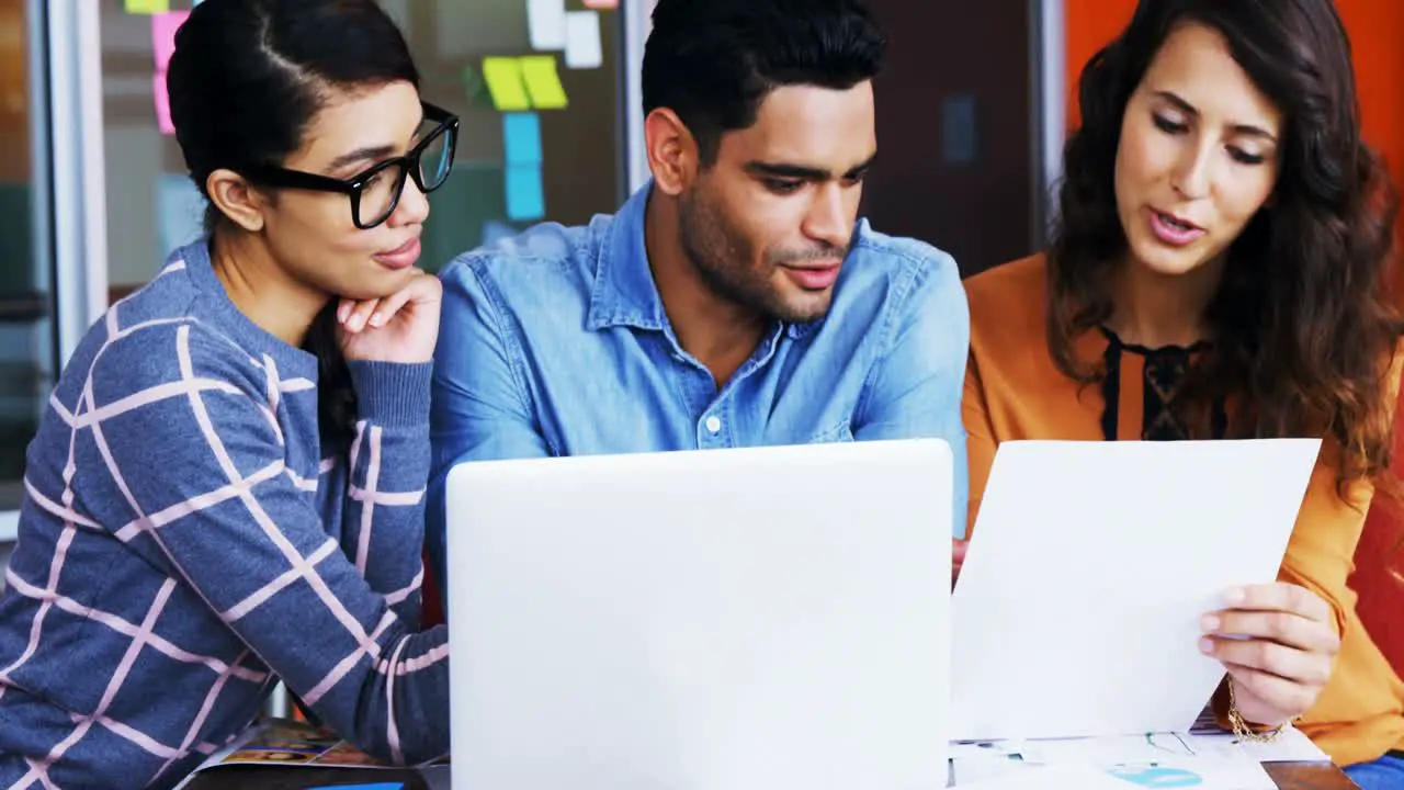 Smiling graphic designers discussing over laptop in meeting