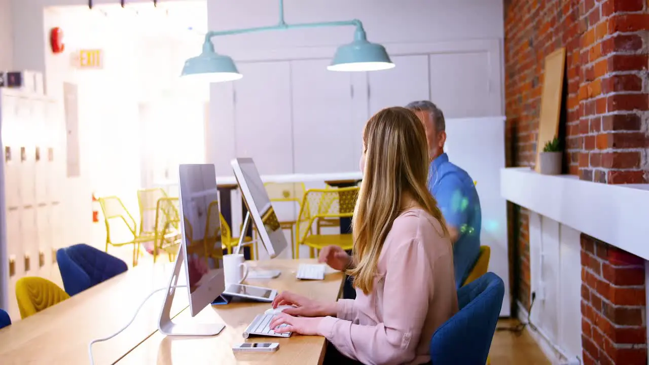 Business executives talking while working on computer