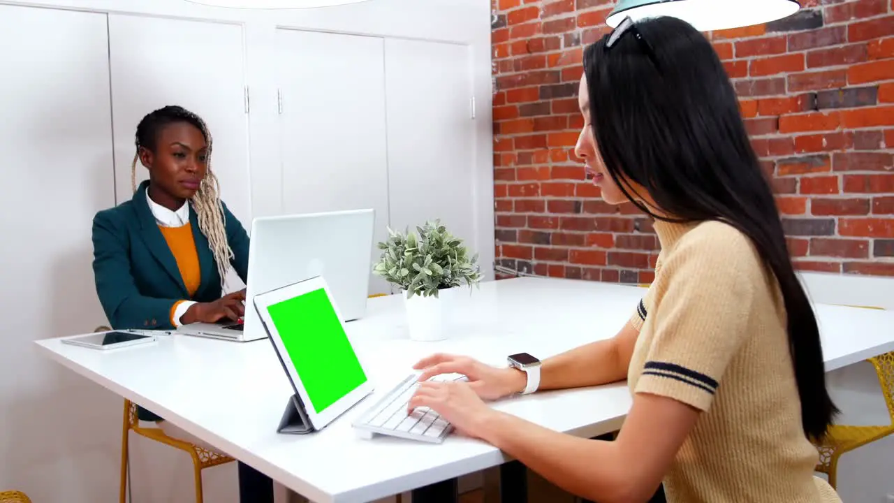 Female executives using laptop and digital tablet at desk