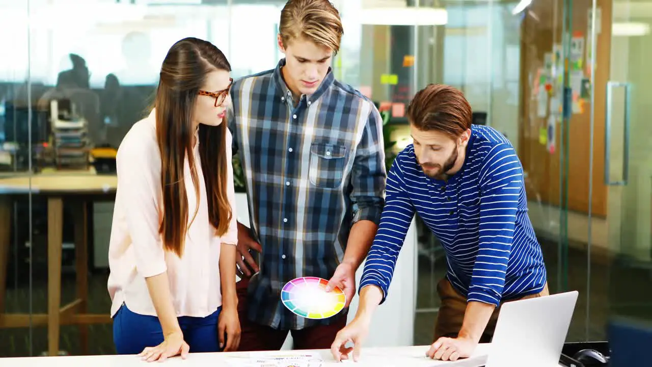 Graphic designers interacting with each other while working in office