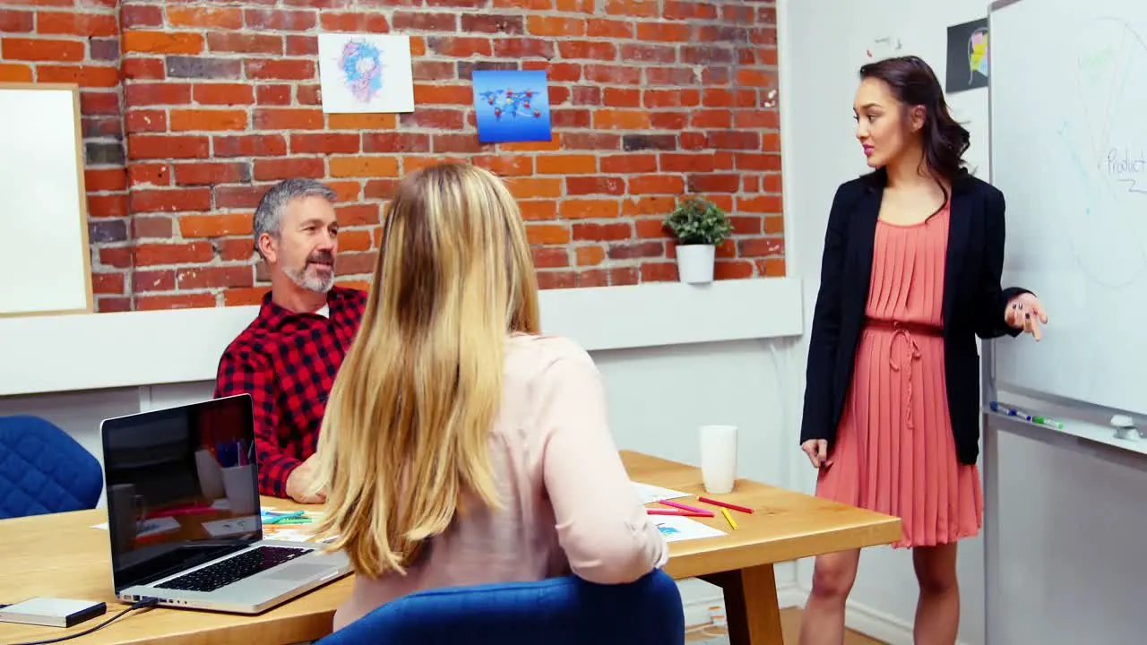 Business executives discussing over whiteboard during meeting