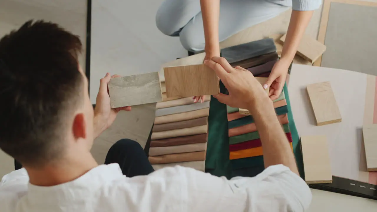 Top view Two spouses choose a finish for their home look at samples of wood fabric and wallpaper