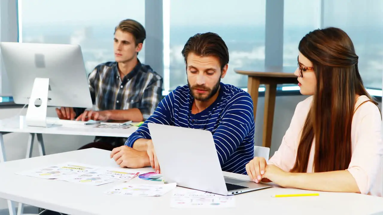 Graphic designers discussing over laptop at desk