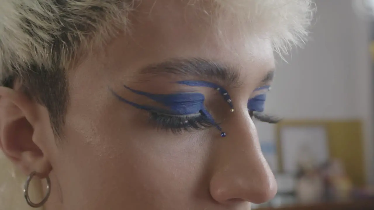 Close up shot of a young woman using eyeliner to create a creative purple makeup look