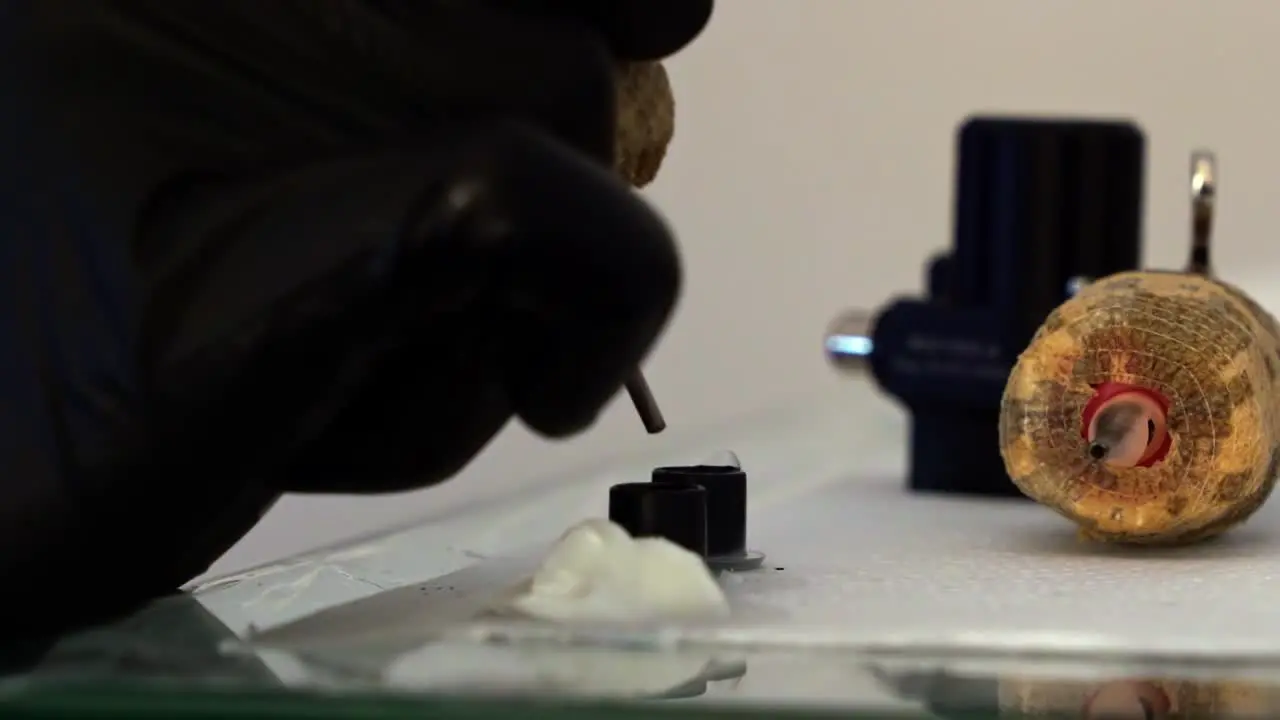 Close up slow motion handheld shot of the hand of a tattoo artist dipping their tattoo gun into a small container of black ink to work on a client