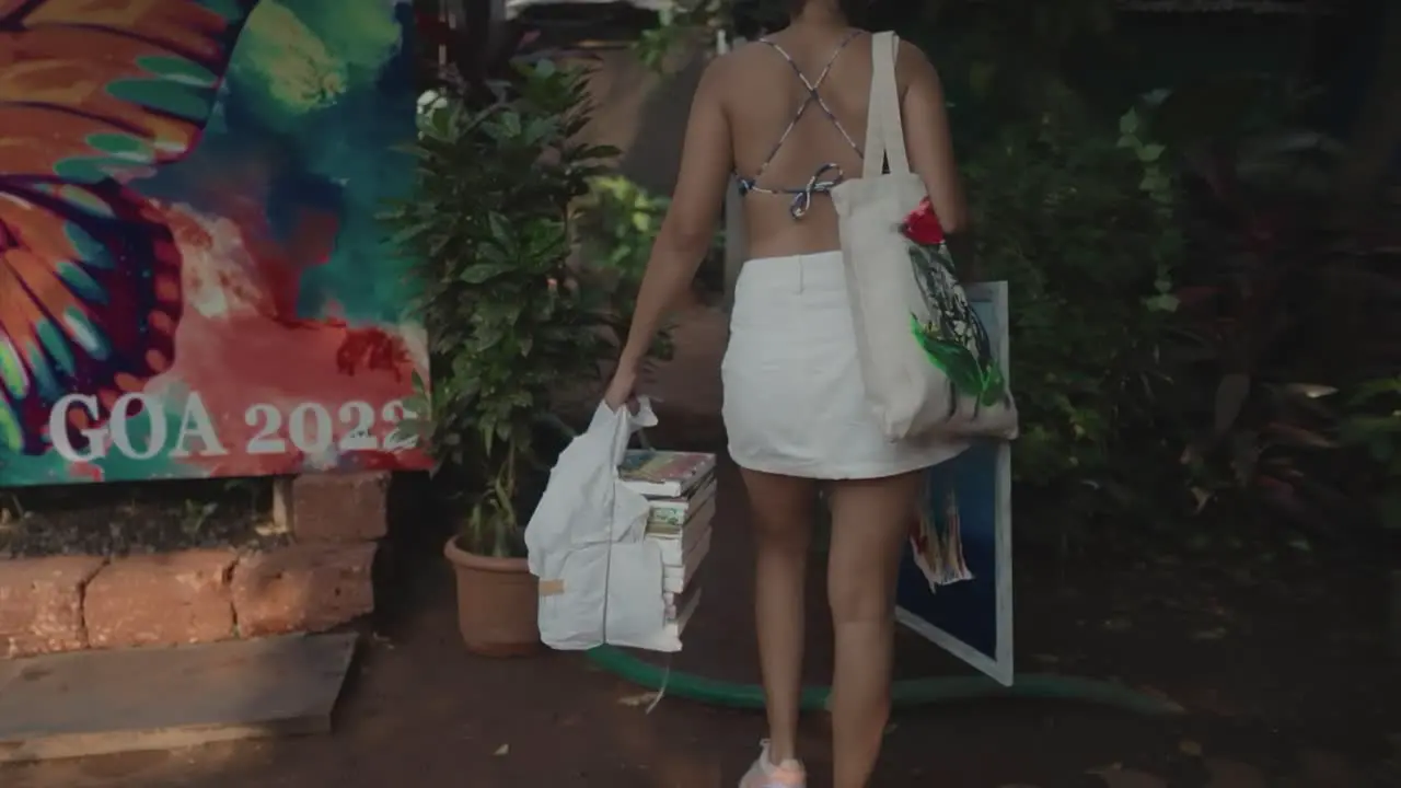 Slow Motion shot of a young Indian artist entering an art gallery with some of her artworks and other art tools