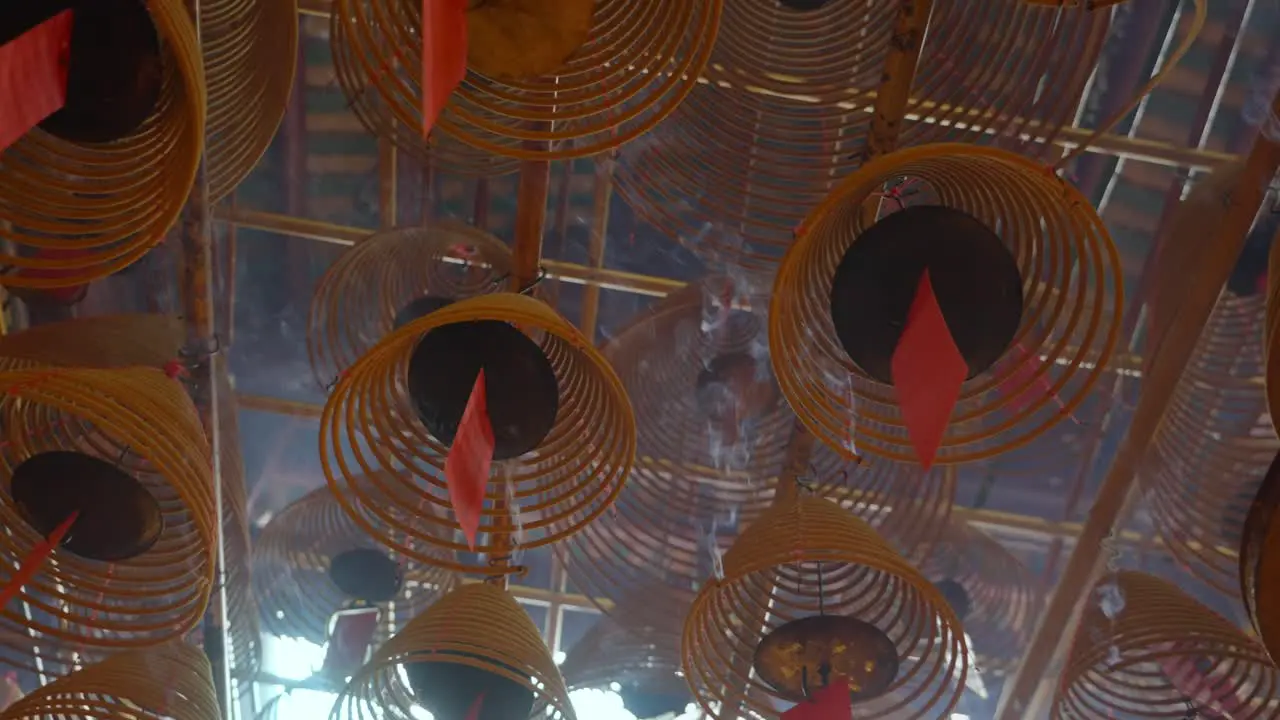 Cinematic shot of circular incenses attach to the roof burning slowly and diffusing smoke