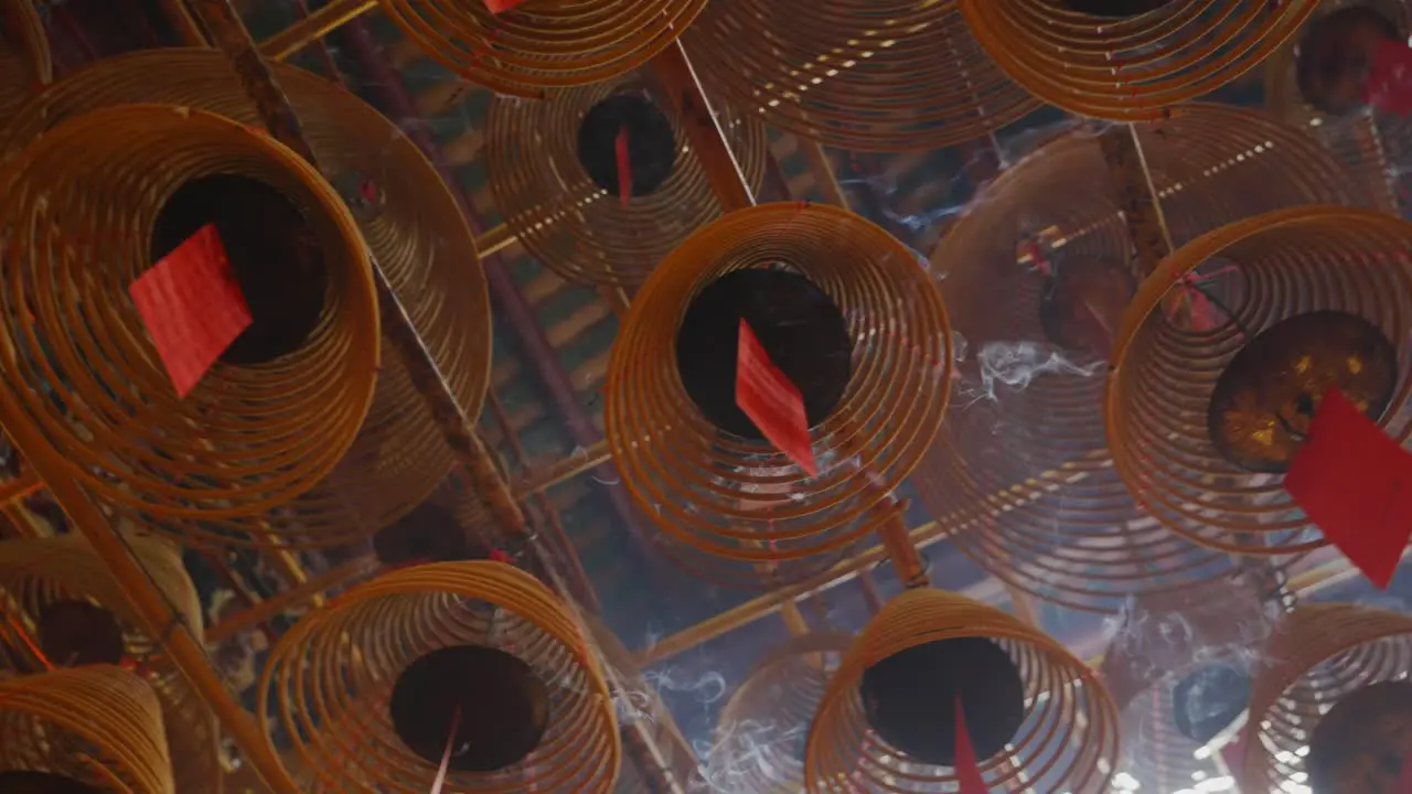 Cinematic shot of circular incenses attach to the roof burning slowly and diffusing smoke-2