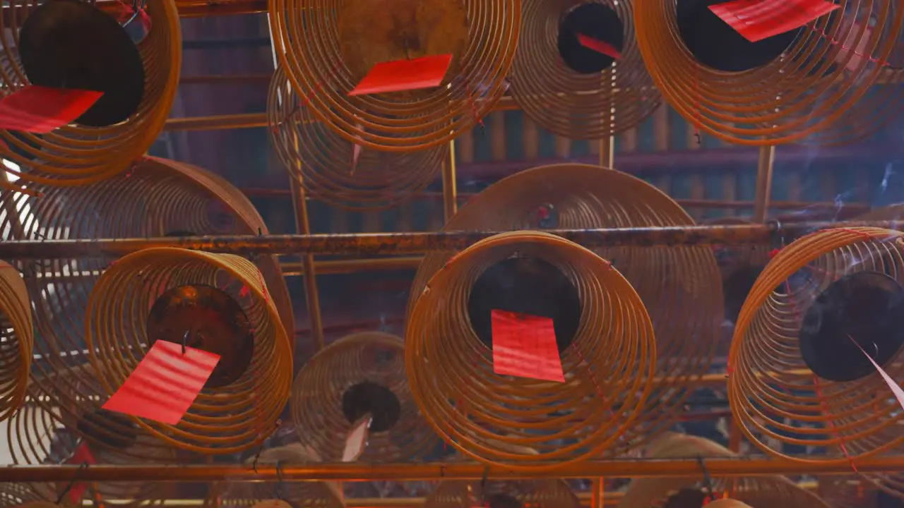 Cinematic shot of circular incenses attach to the roof burning slowly and diffusing smoke-4