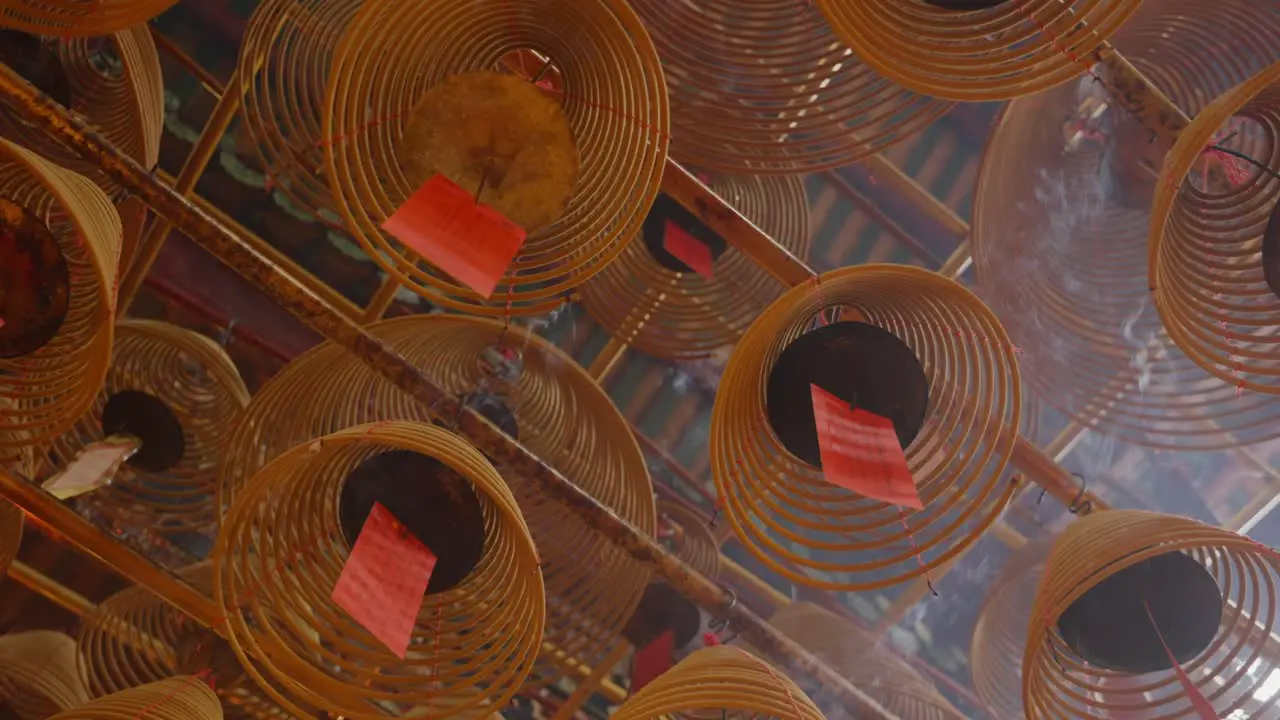 Cinematic shot of circular incenses attach to the roof burning slowly and diffusing smoke-5