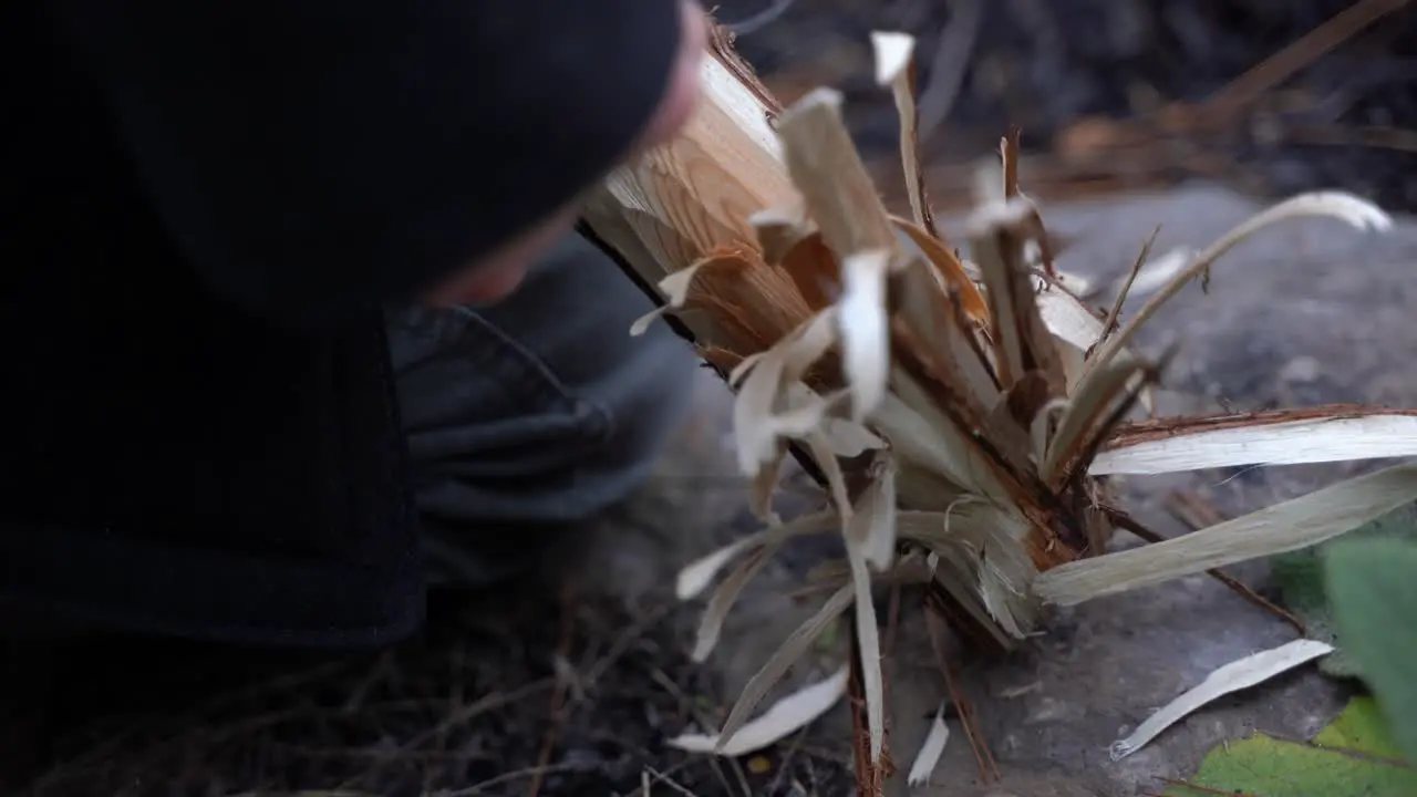 white male shaving woods to get fire ready