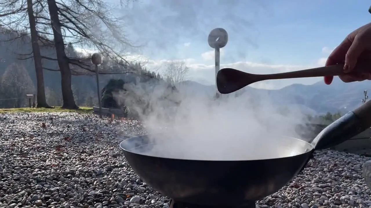 Cooking in a wok over an open fire stirring food