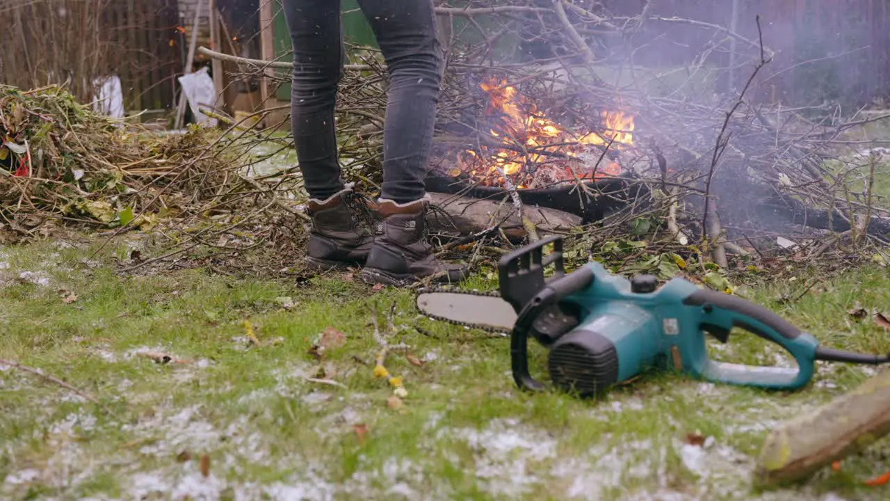 Person putting more branches for burning after tree pruning late autumn