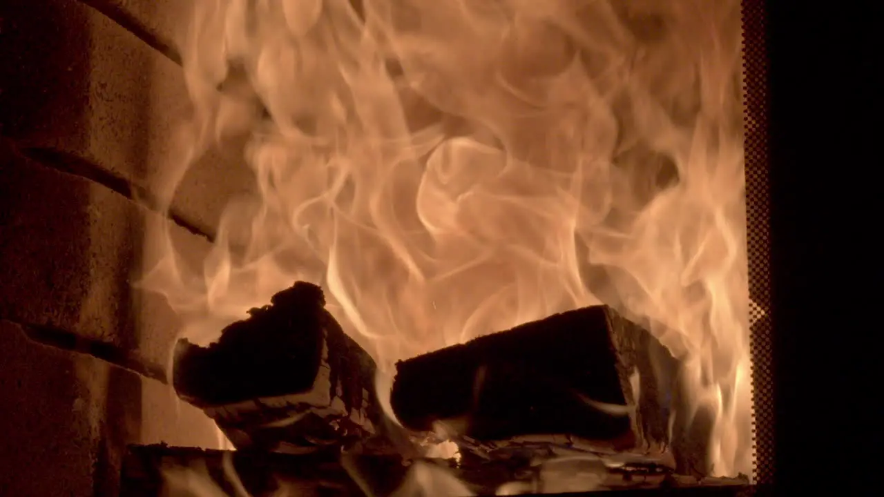 Close up shot of a roaring fire burning large logs high golden orange flames