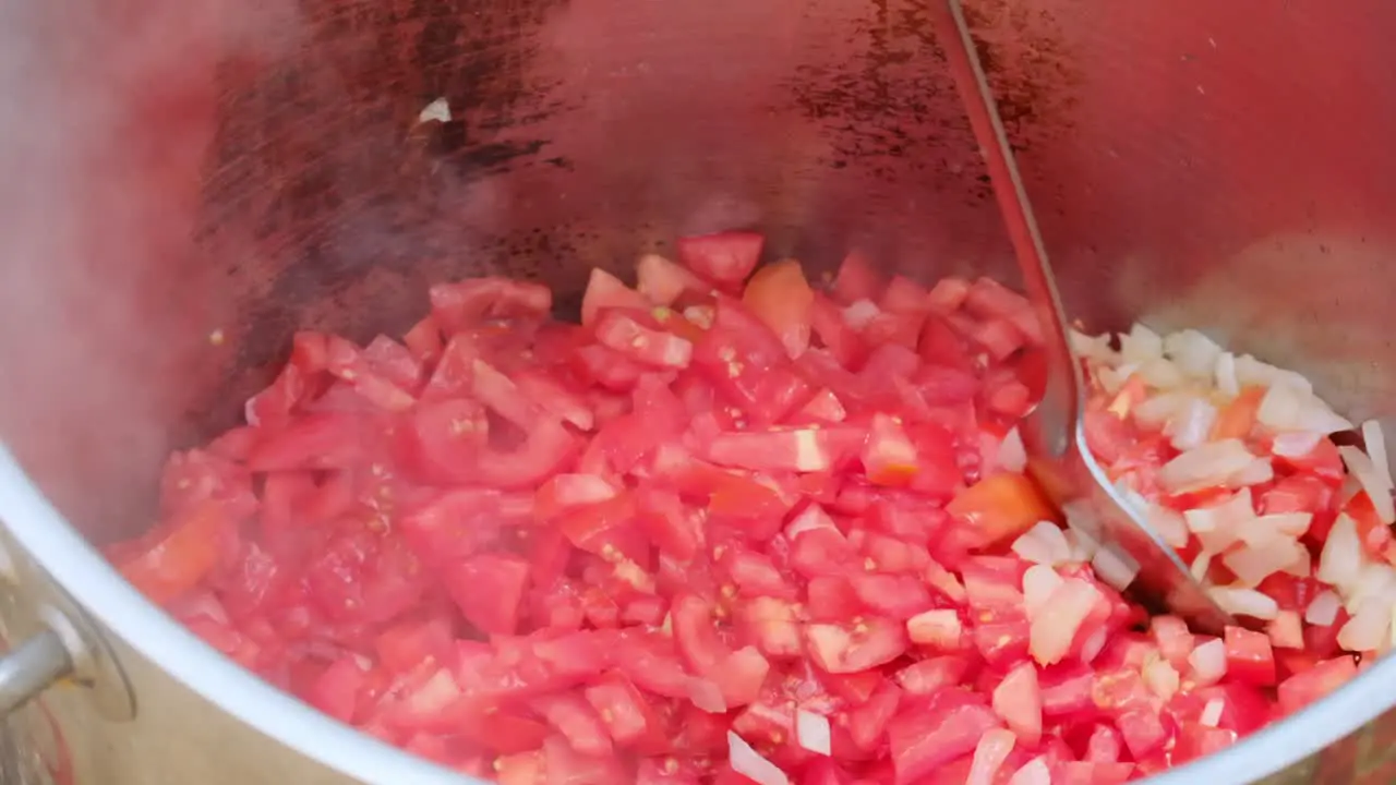 slow motion of Kosher military food pot with onions and tomatoes frying in the oil while mixed