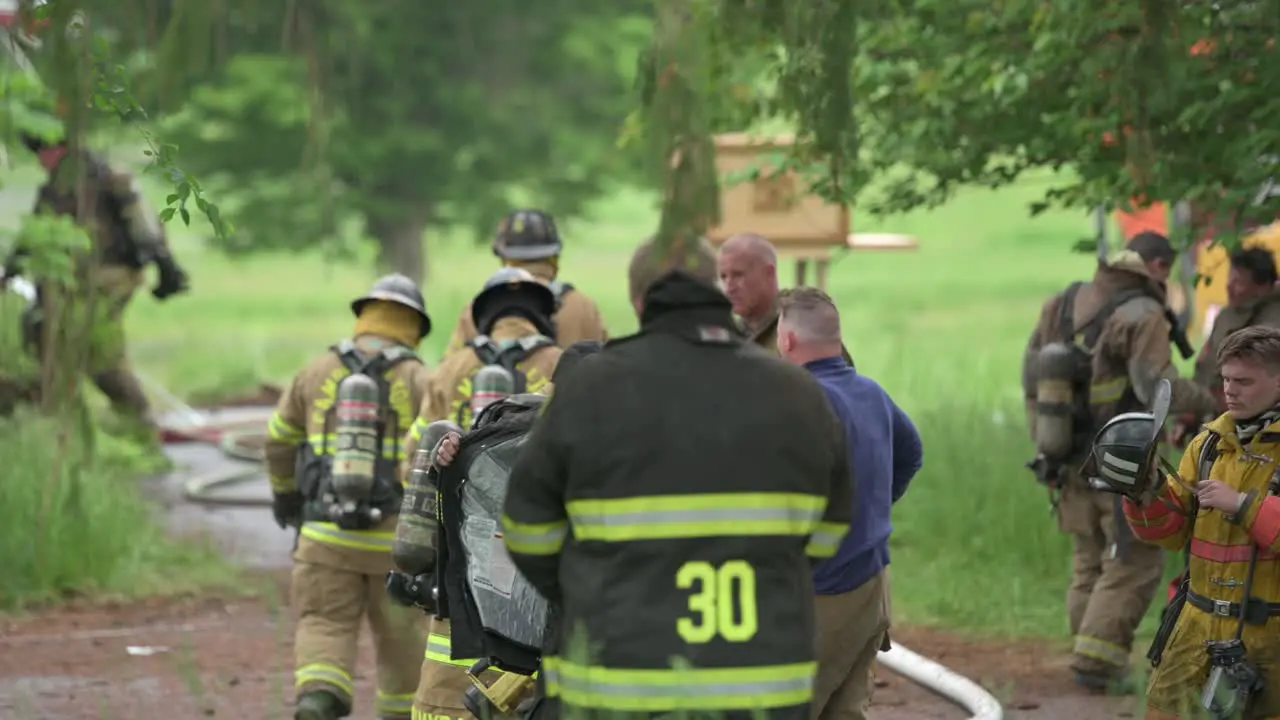 A group of firemen putting on various gear preparing to entire a house on fire