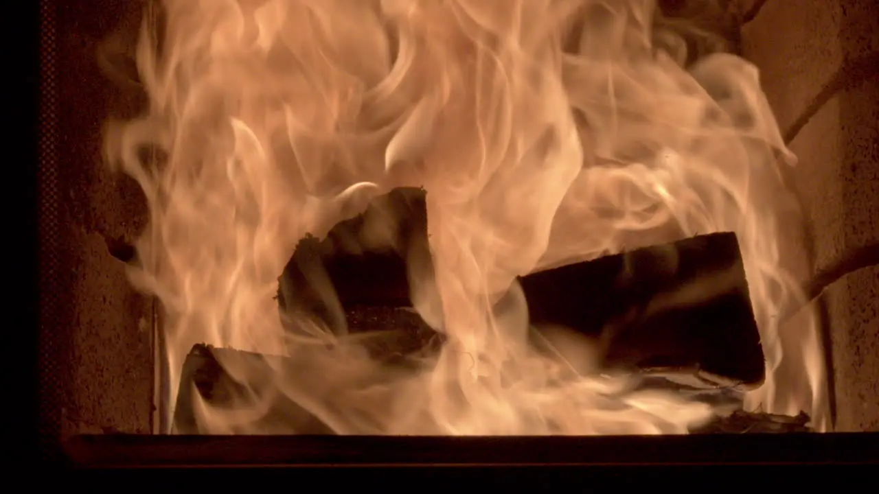 Closeup truck shot of some large logs burning inside a brick fireplace high fast flames