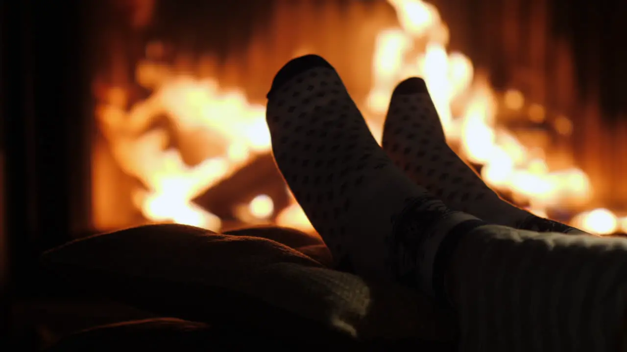 Legs In Socks Are Heated By The Fireplace In Winter Evening