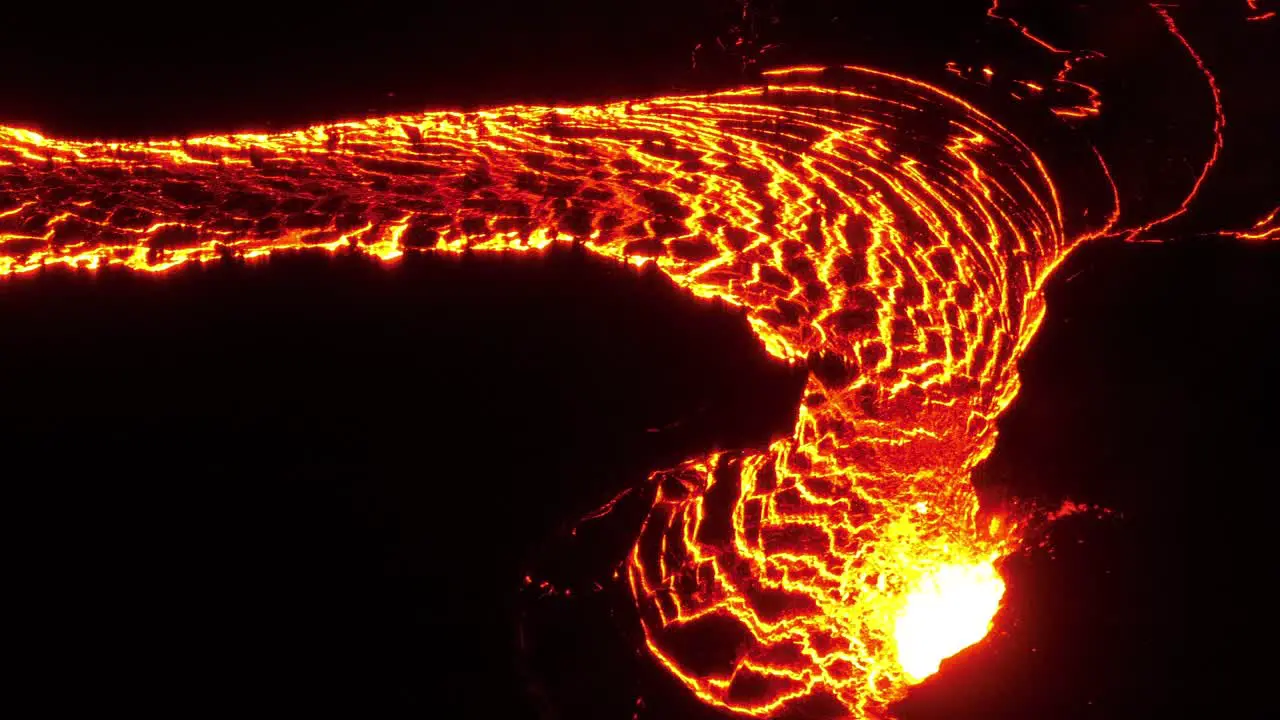 A river of flowing lava from erupting volcano at night