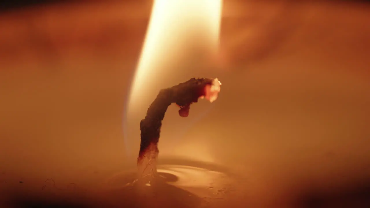 A macro shot of a lit candle wick with a gentle flame