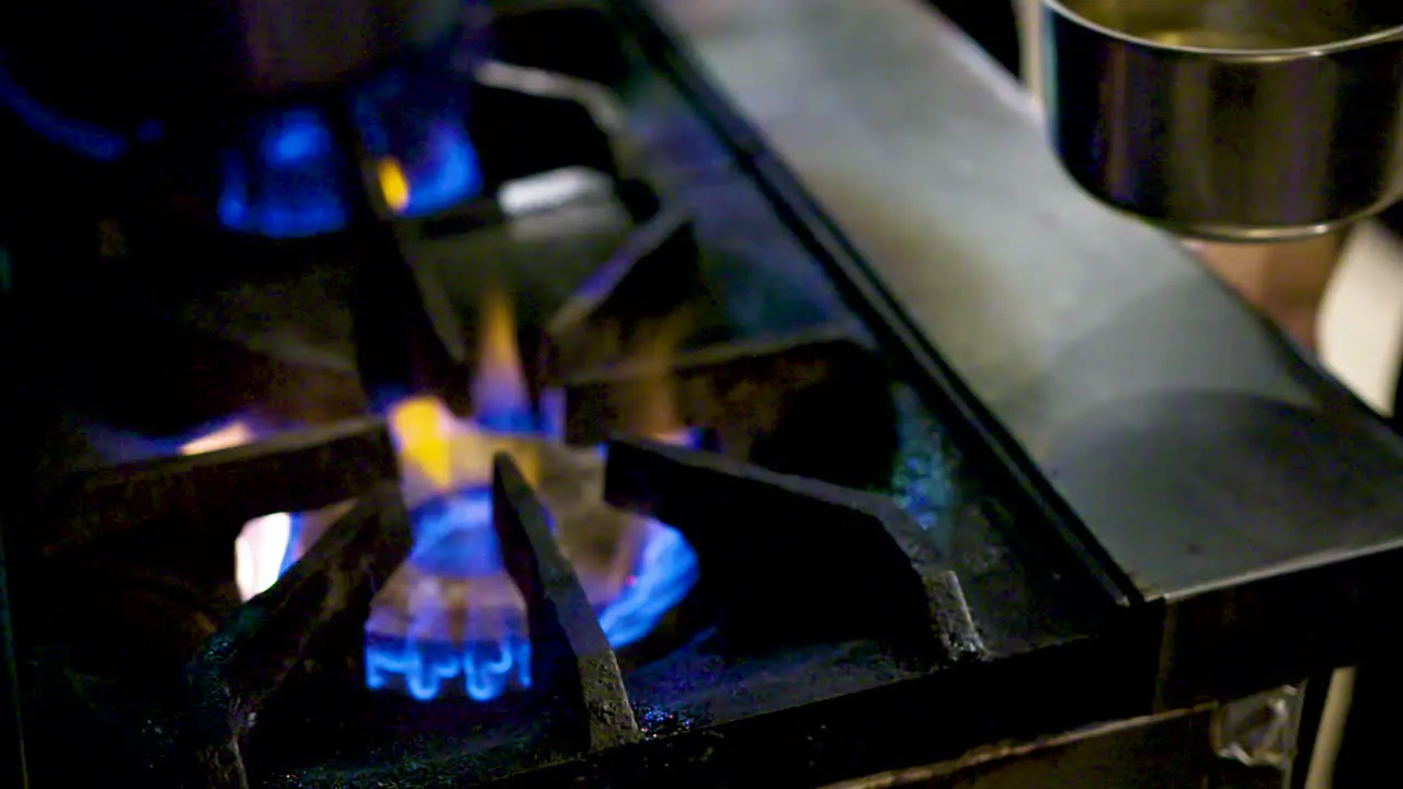 Chef taking a pot off a gas burner in a commercial kitchen