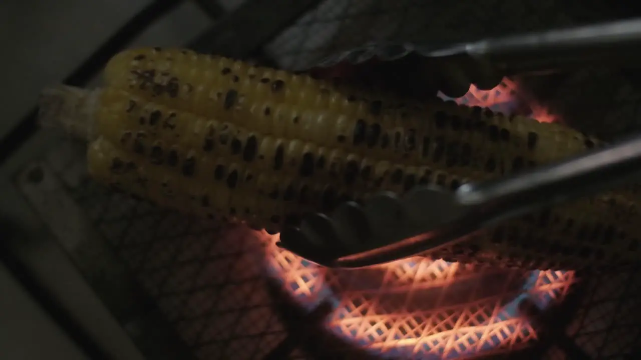 placing Corn on the cob cooking on a gas stove over a grill from above slow motion