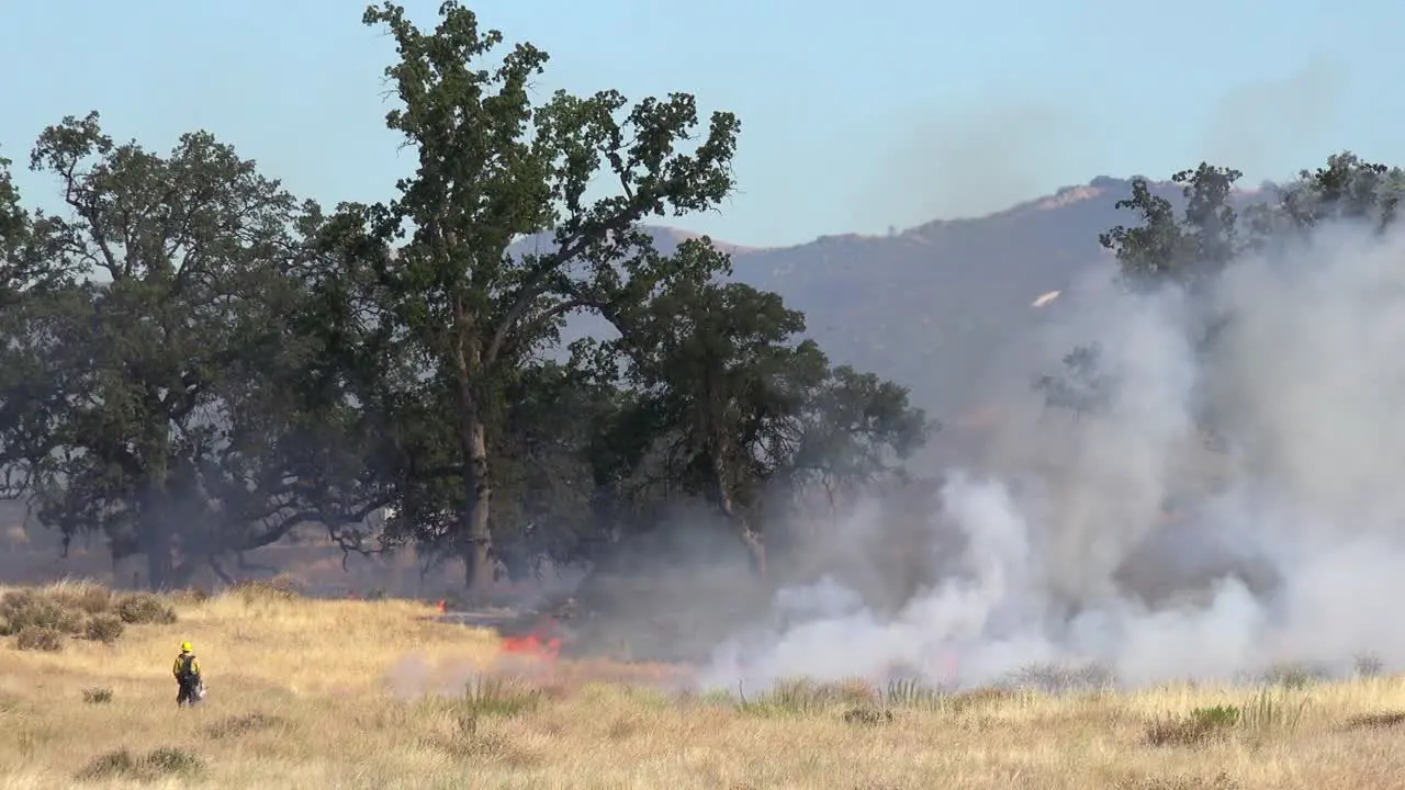 A wildfire burns in the hills of Central California as firefighters look on