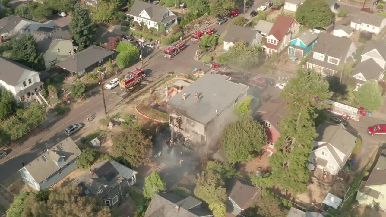 Pan down aerial shot of fire fighters surrounding a burning building