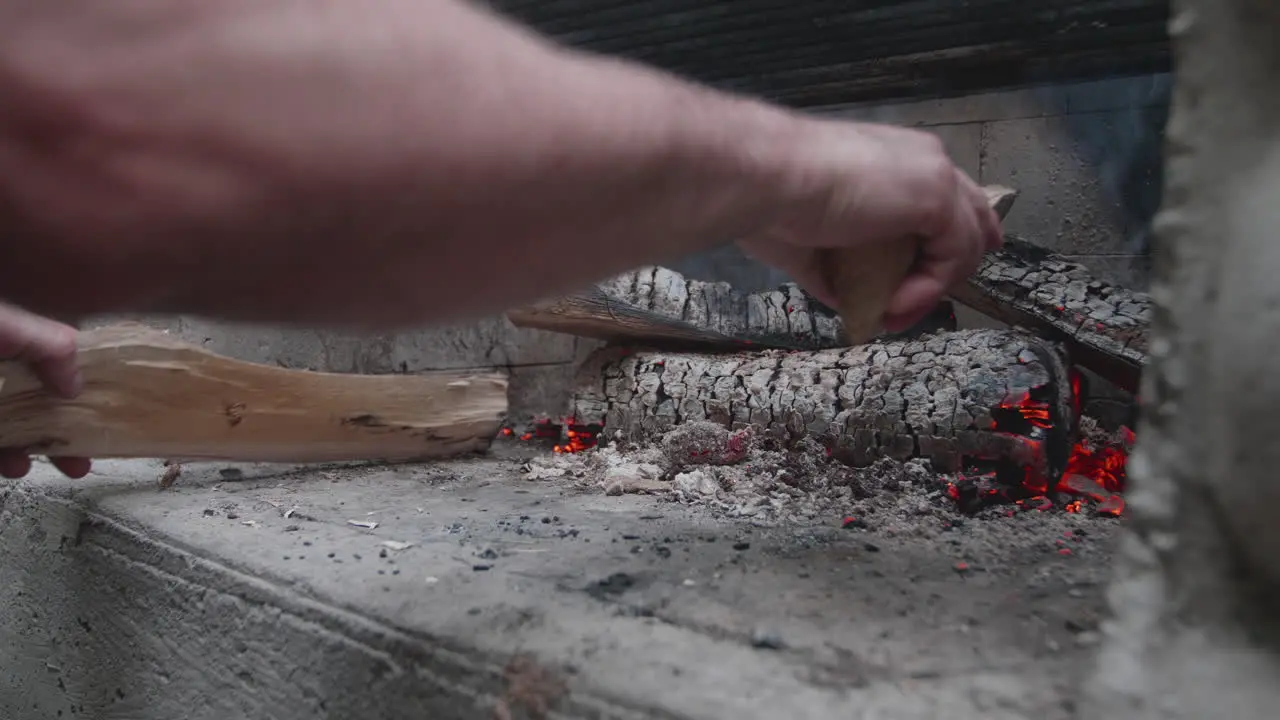 Hands adjusting woods in a campfire