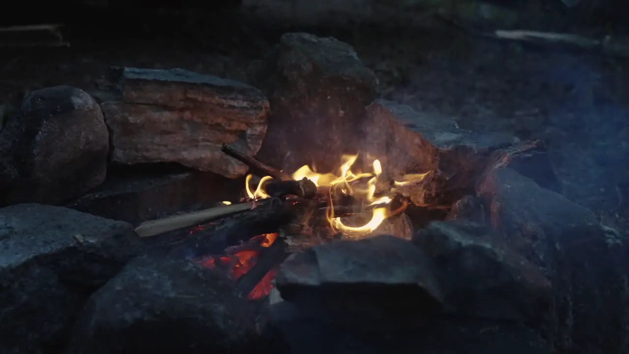 Bright Orange Flames licking up in the air Slow Motion shot of small campfire burning wood surrounded by stones 4k wide shot