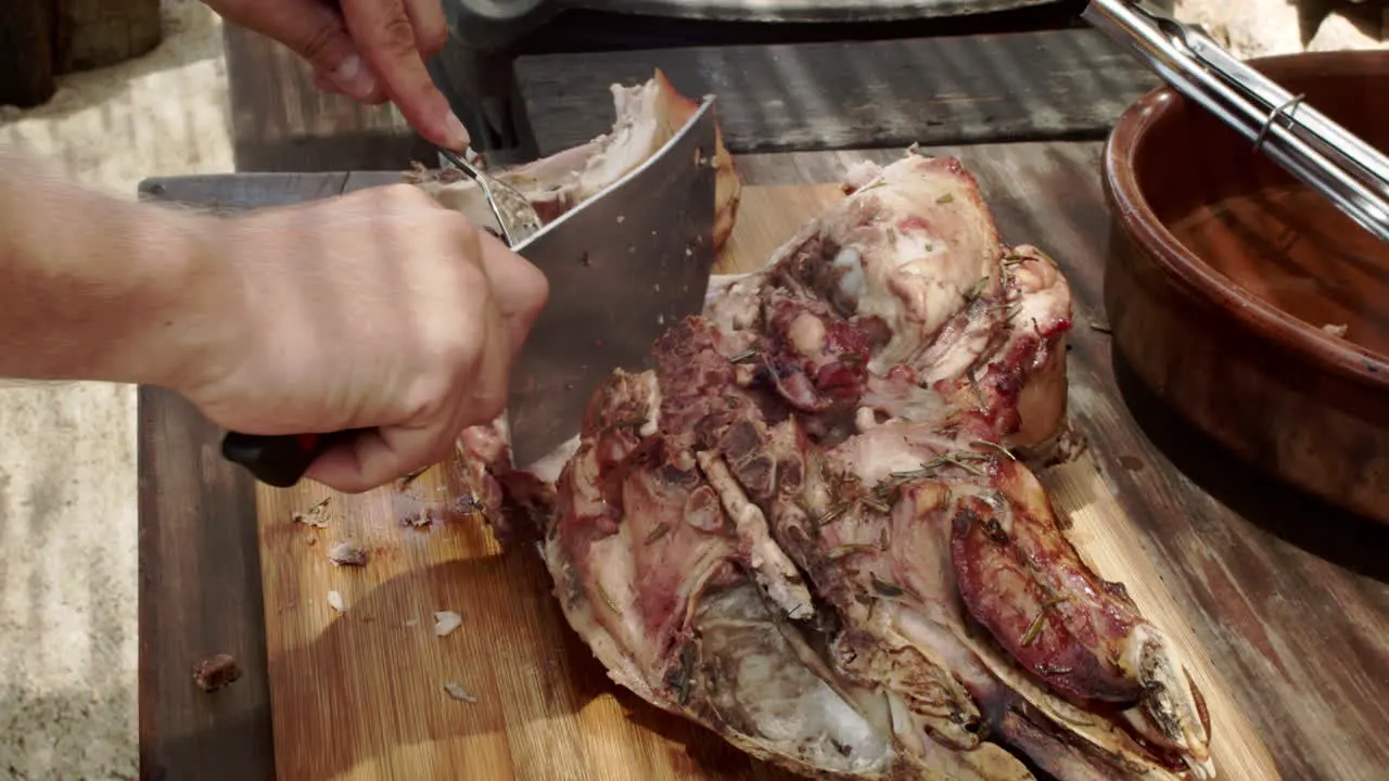 Man chops roasted pig head at a picnic