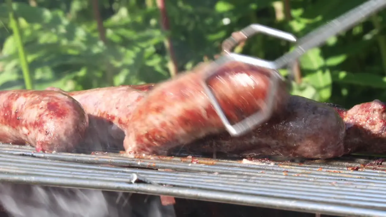 Tongs turning sausages on barbecue