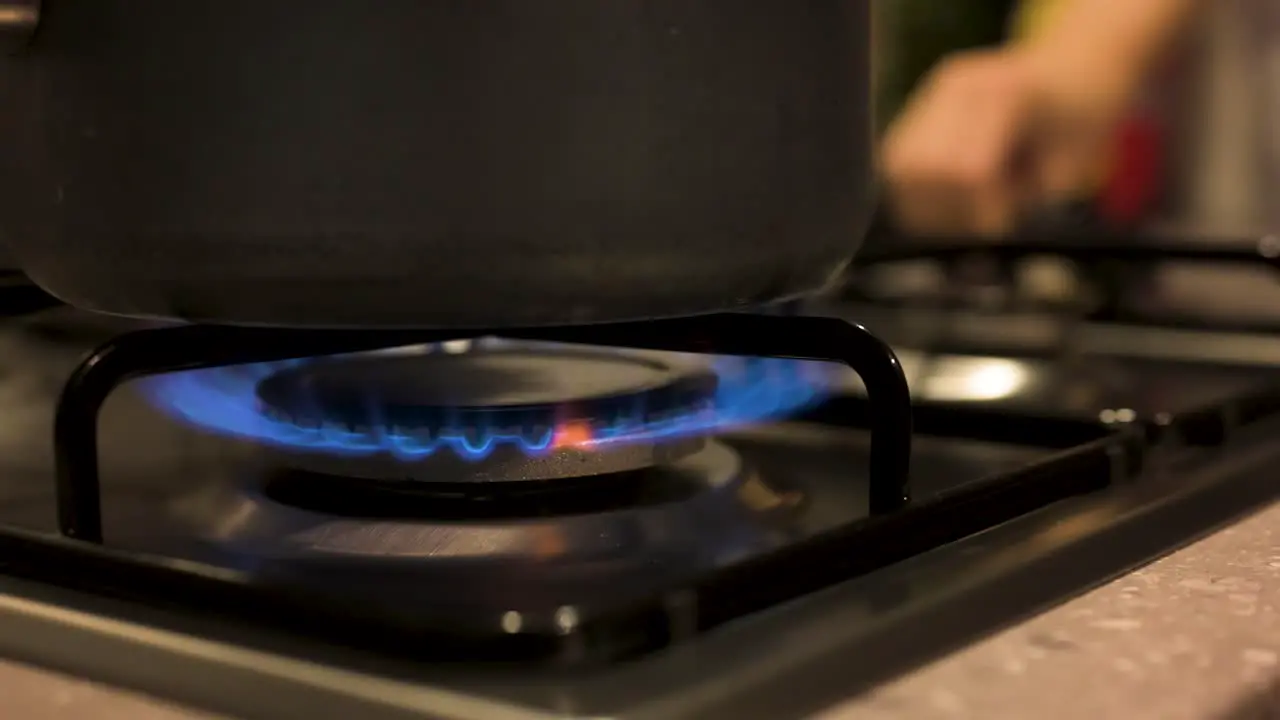 Turning gas stove on with pot on top close up slow motion