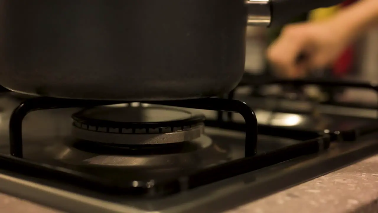 Placing pot on stove and turning gas stove on close up slow motion