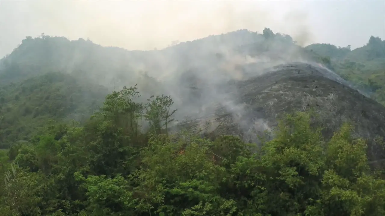 Aerial over a slash and burn mountainside burning