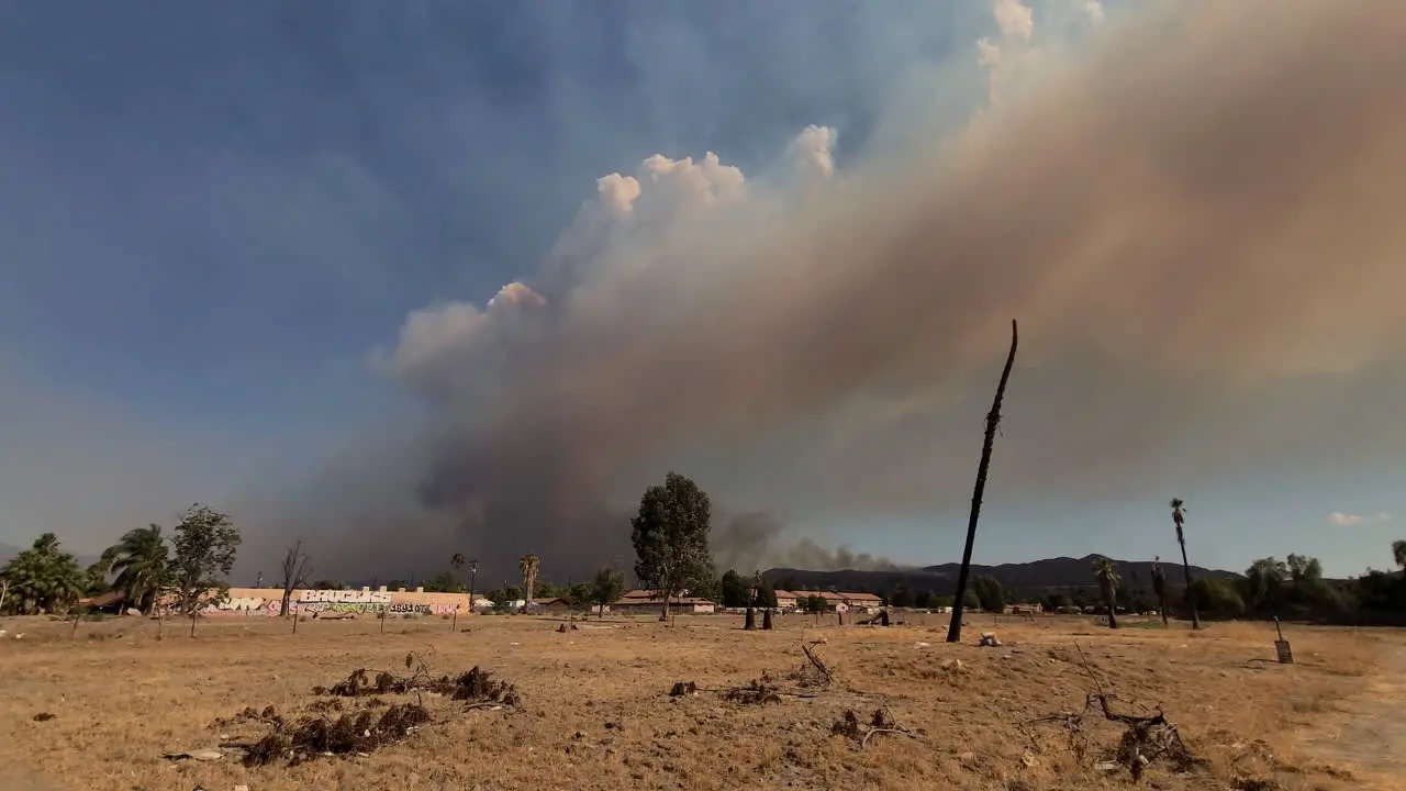 Large dust cloud and smoke plume flying through the blue sky from wildfire in the desert