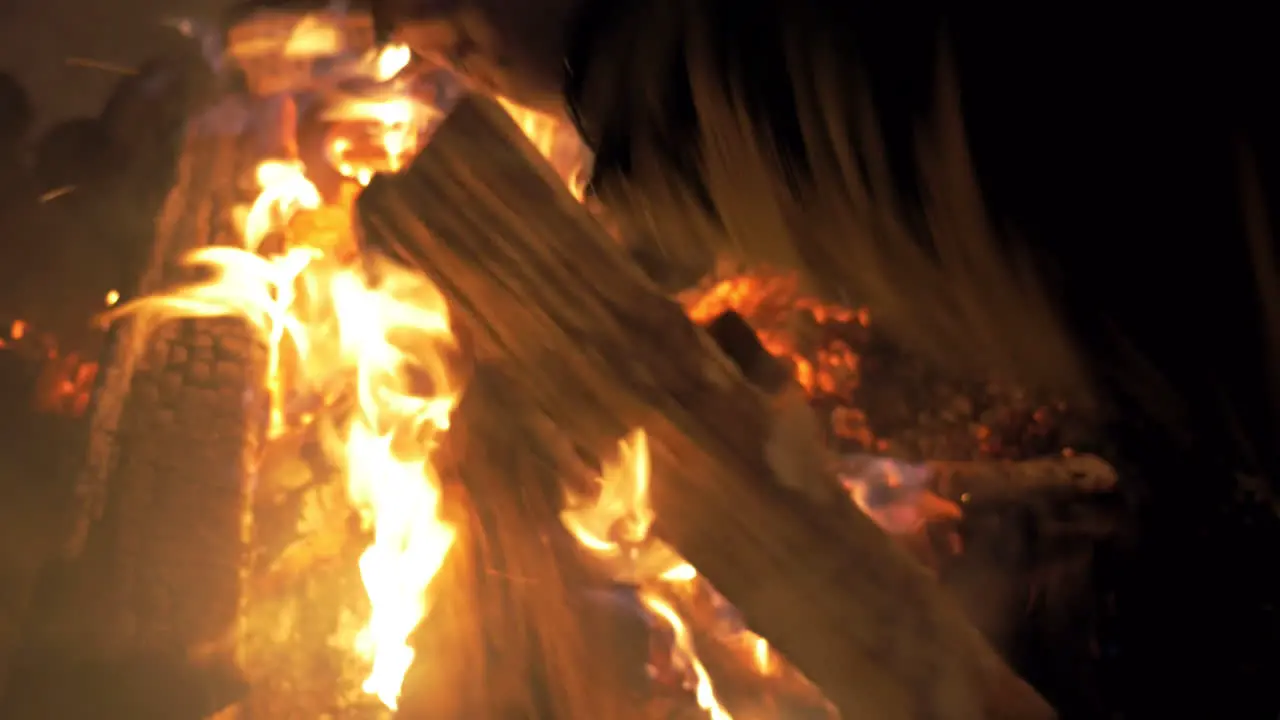 Woman putting more wood in the fire at night