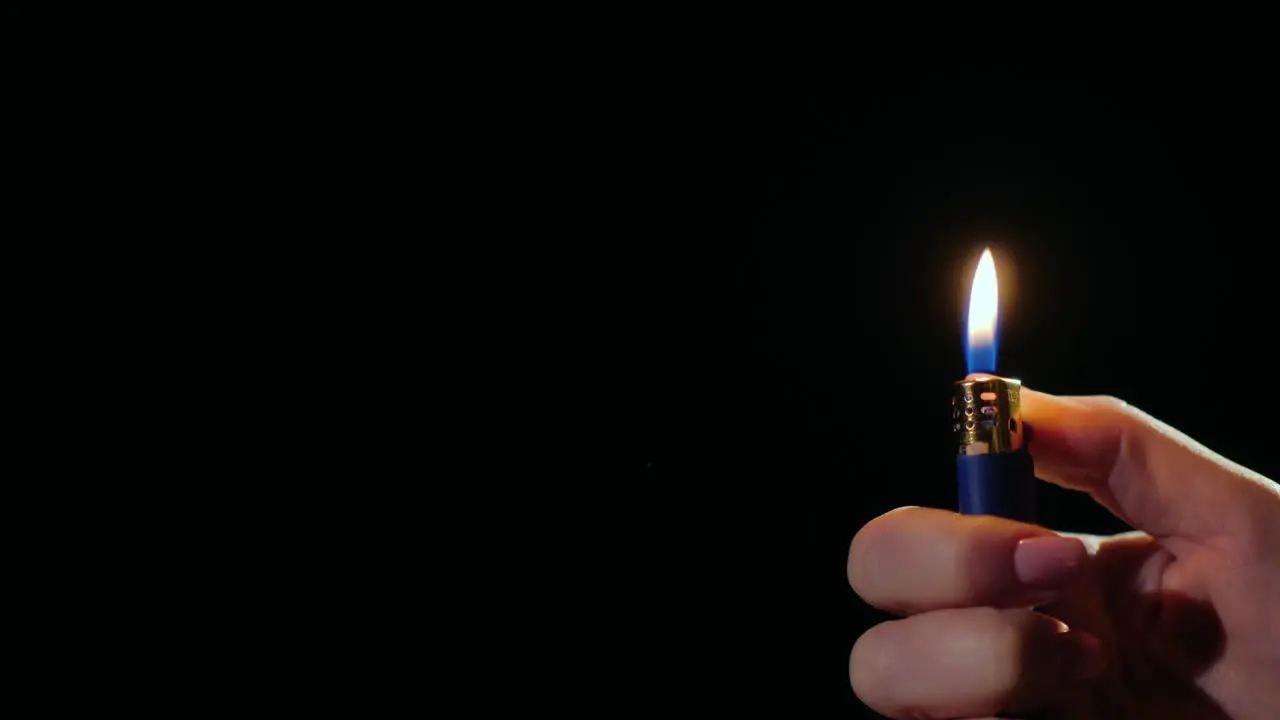 Hand Ignites Flames On Lighter On Black Background