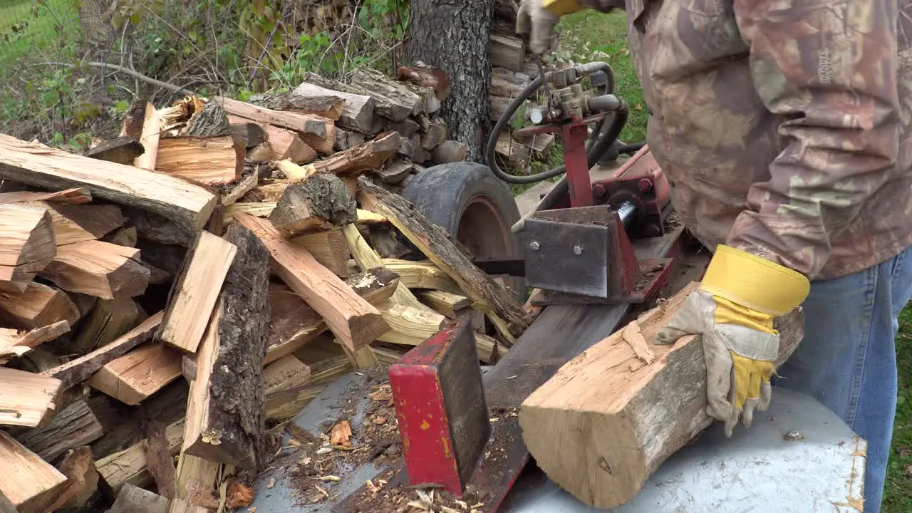 A man using a hydraulic log splitter to make firewood for the winter