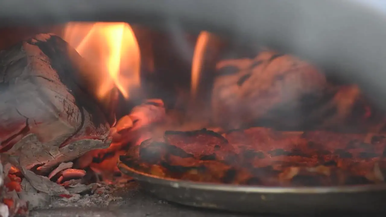 4k close-up of outdoor pizza oven with fire smoke and logs