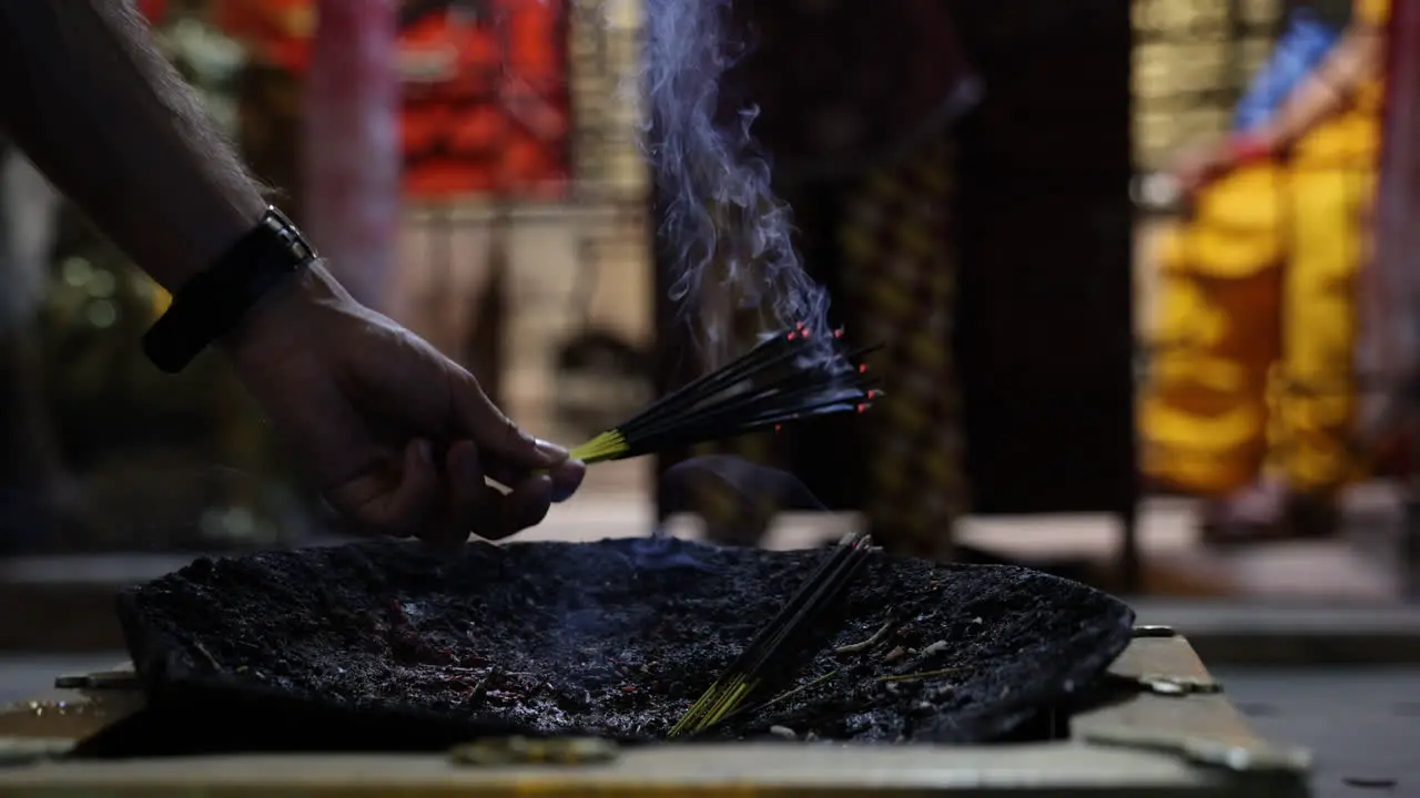 Worshipper places burning incense at a temple