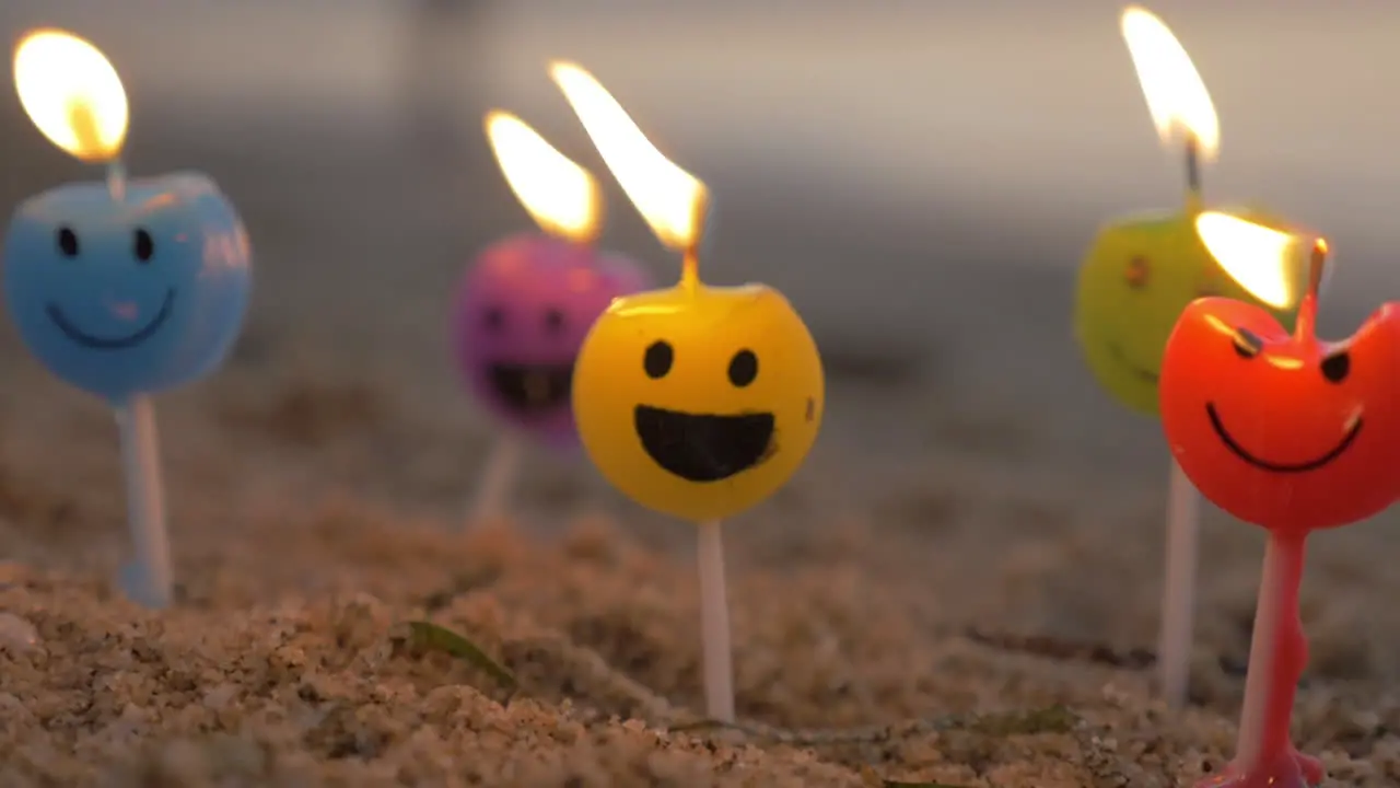 Colorful smiley candles on the beach