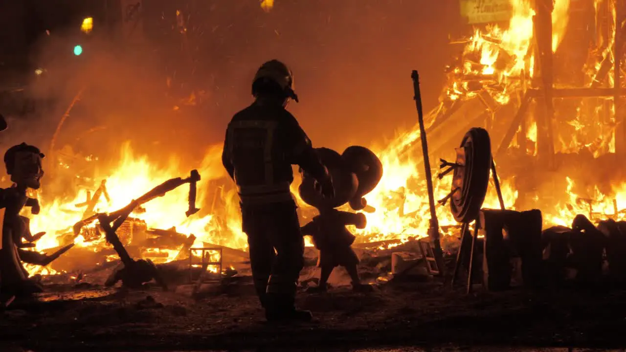 Firefighter burning ninots in the fire of La Cream on Fallas celebration Spain