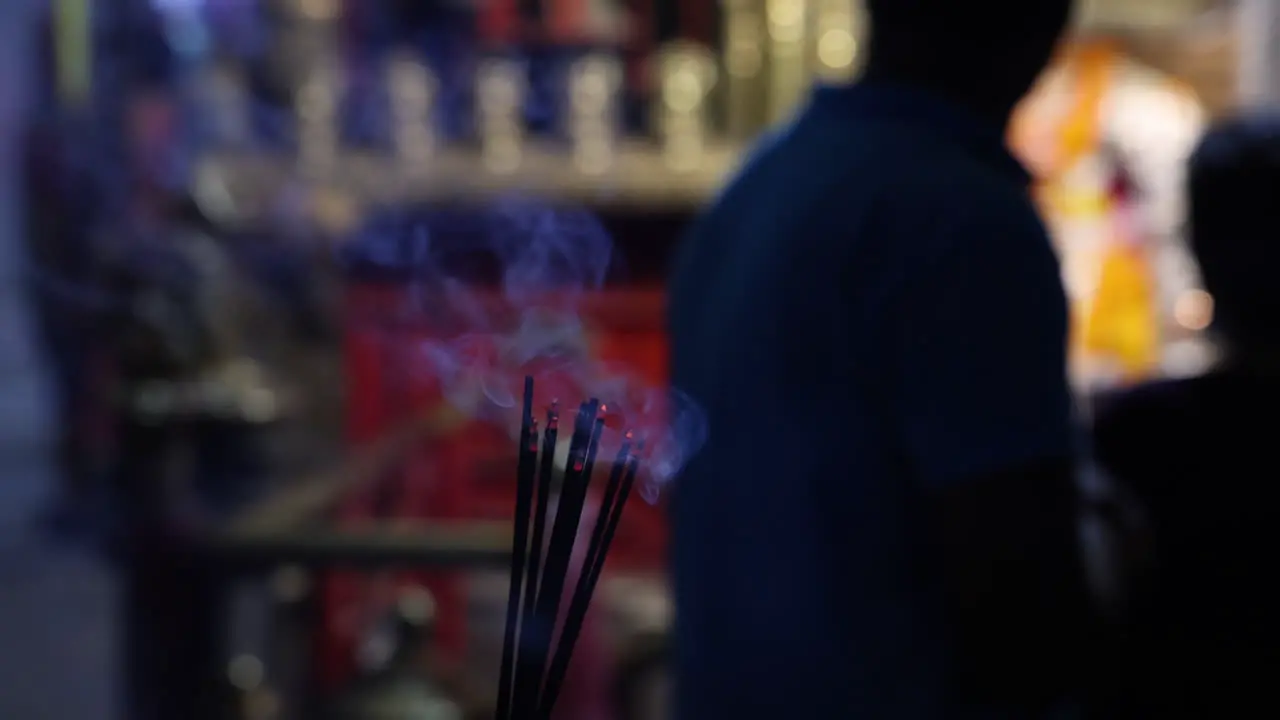 Incense burns while worshippers pray at temple